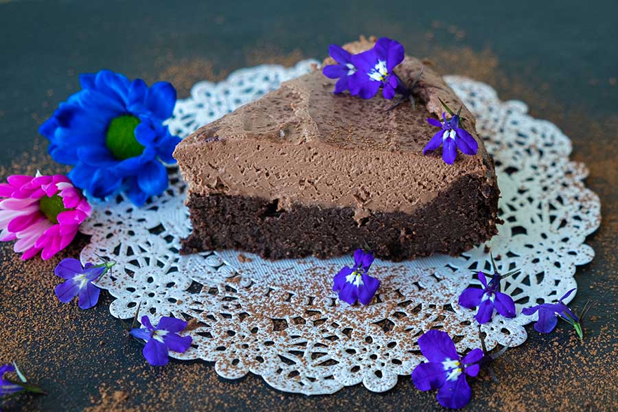 a slice of 2 layer grain free chocolate cake topped with violets for Valnetine’s 