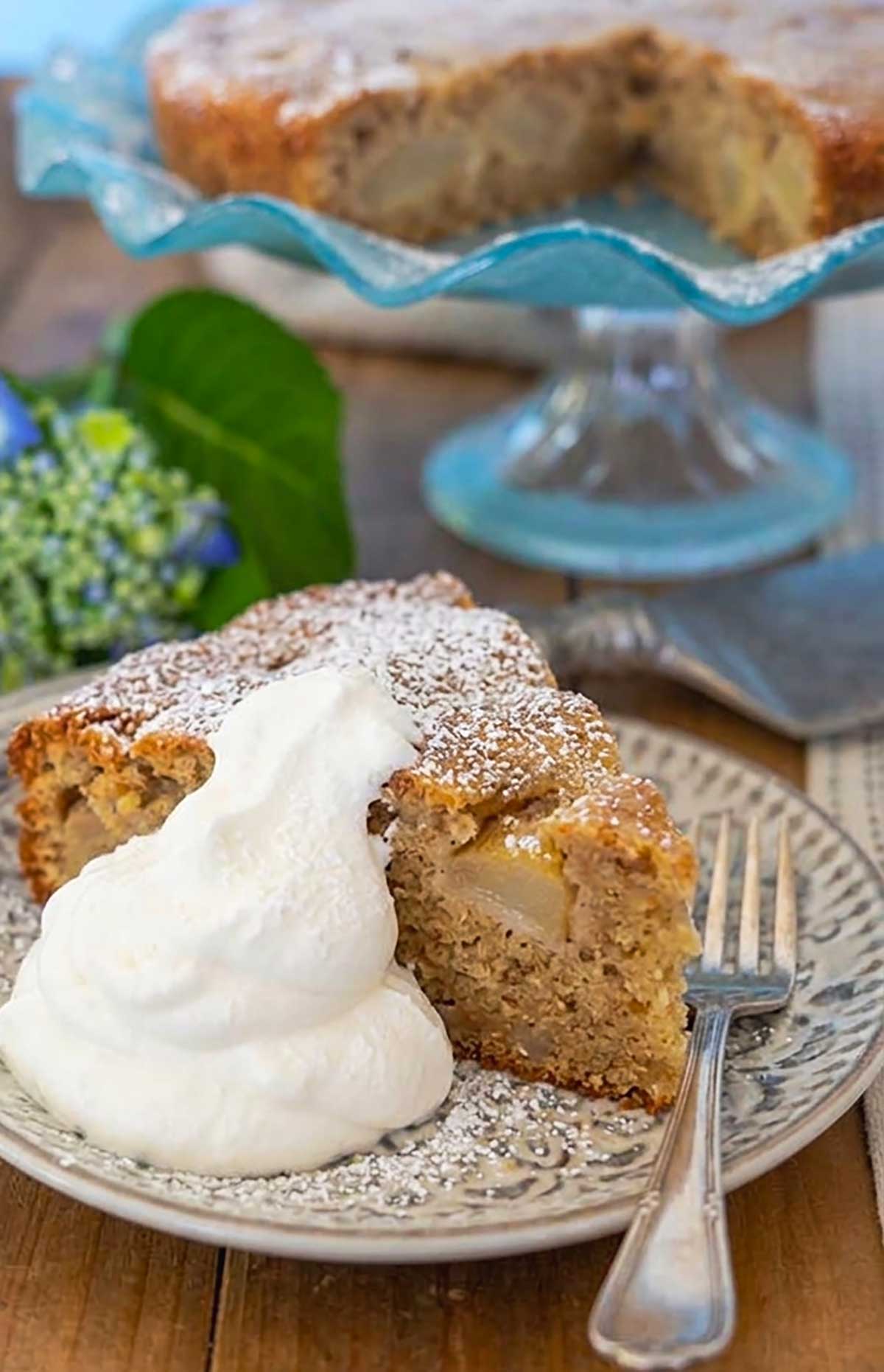 slice of French pear cake on a plate topped with whipped cream