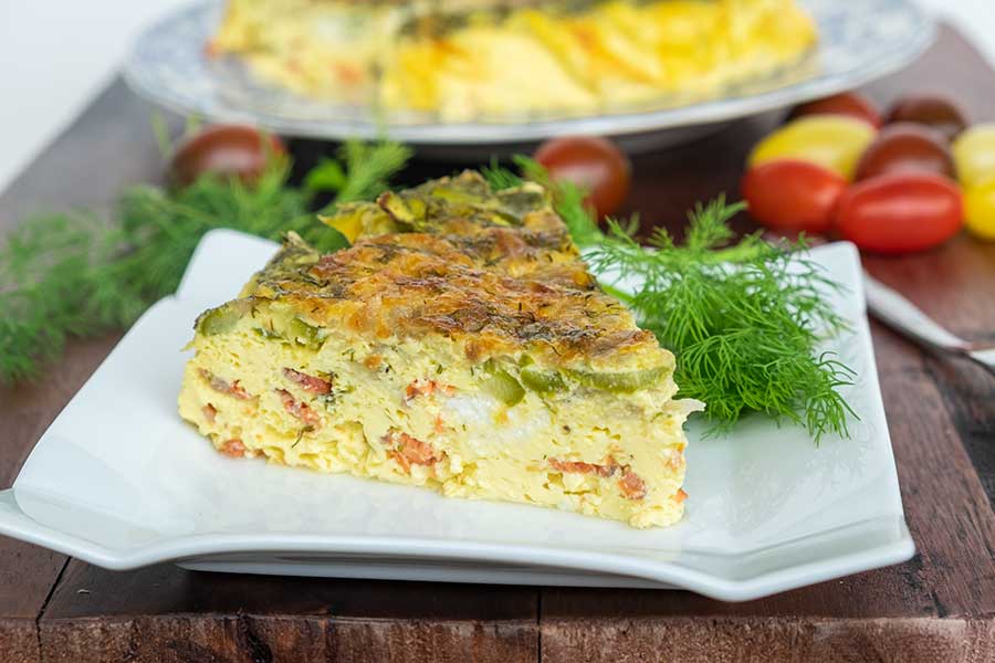 a slice of smoked salmon asparagus quiche on a square plate