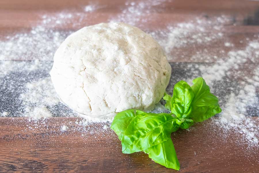 pizza dough on a cutting board dusted with flour