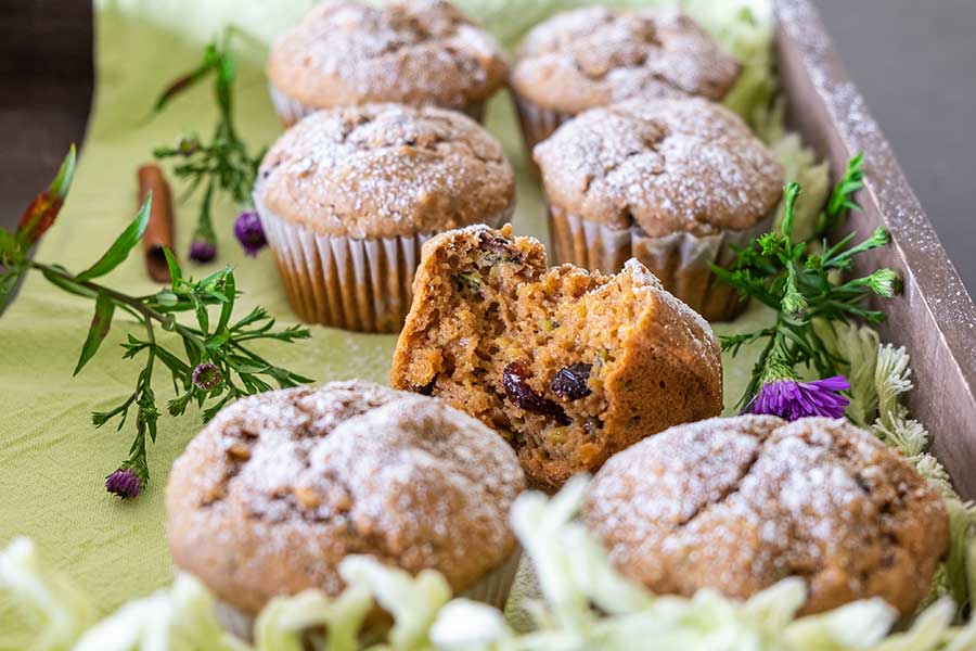 zucchini chai muffins on a tray topped with powdered sugar