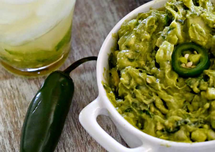 guacamole in a bowl with jalapenos