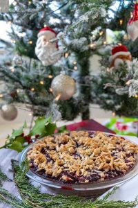 whole gluten free triple berry pie in a pie dish next to a christmas tree
