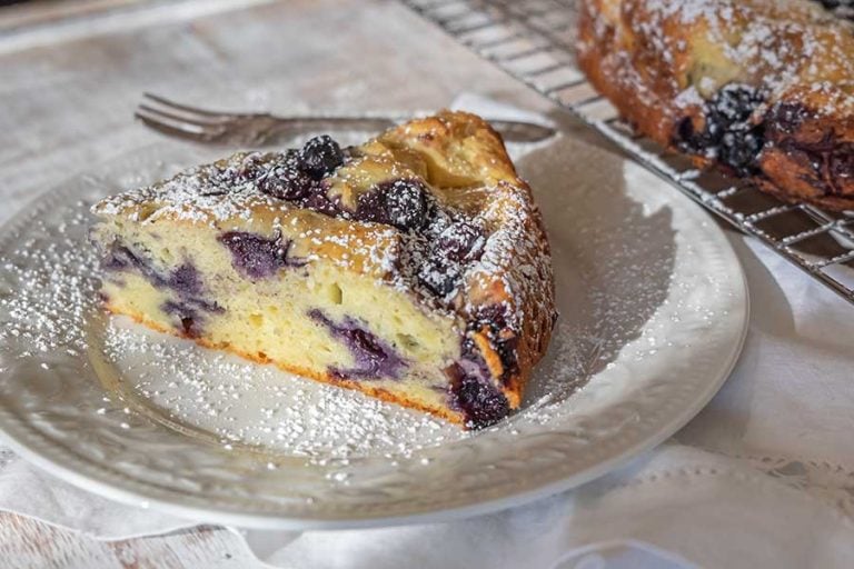 ricotta blueberry breakfast cake on a dessert platter dusted with powdered sugar