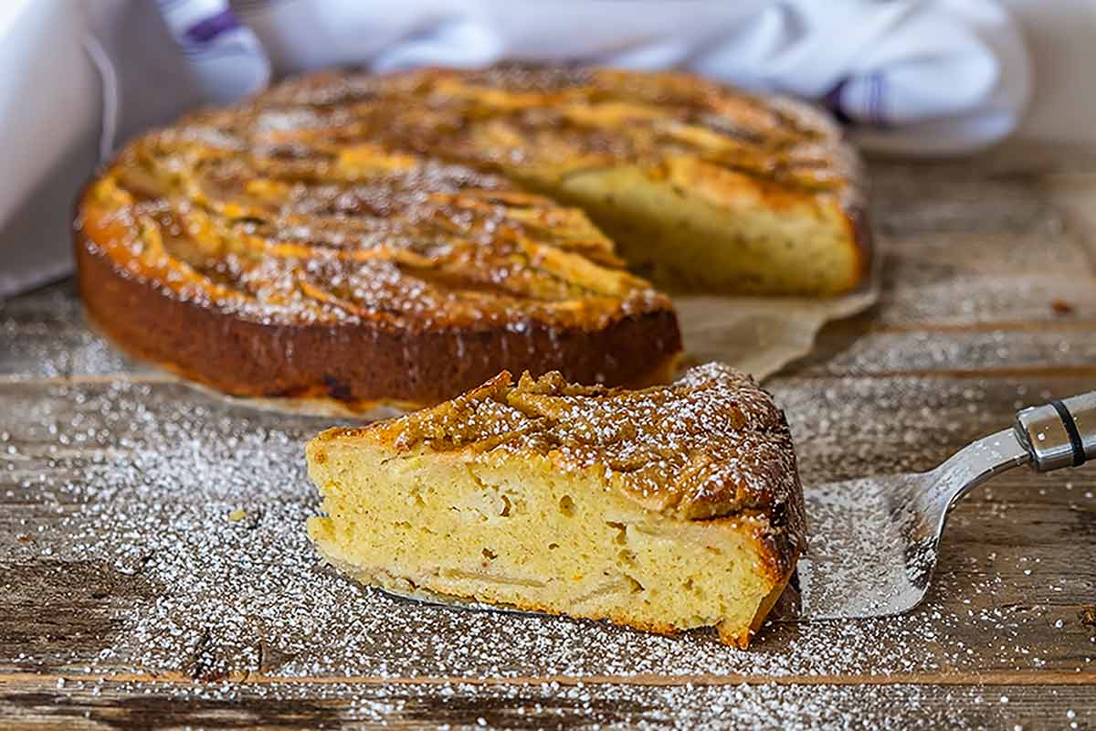 whole breakfast cake layered with apples with one cut slice