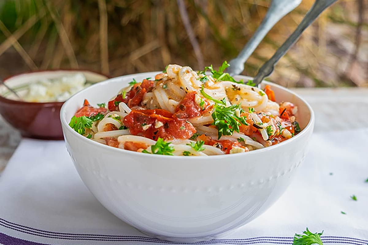 gluten free pasta in a fresh tomato and feta light sauce topped with fresh herbs