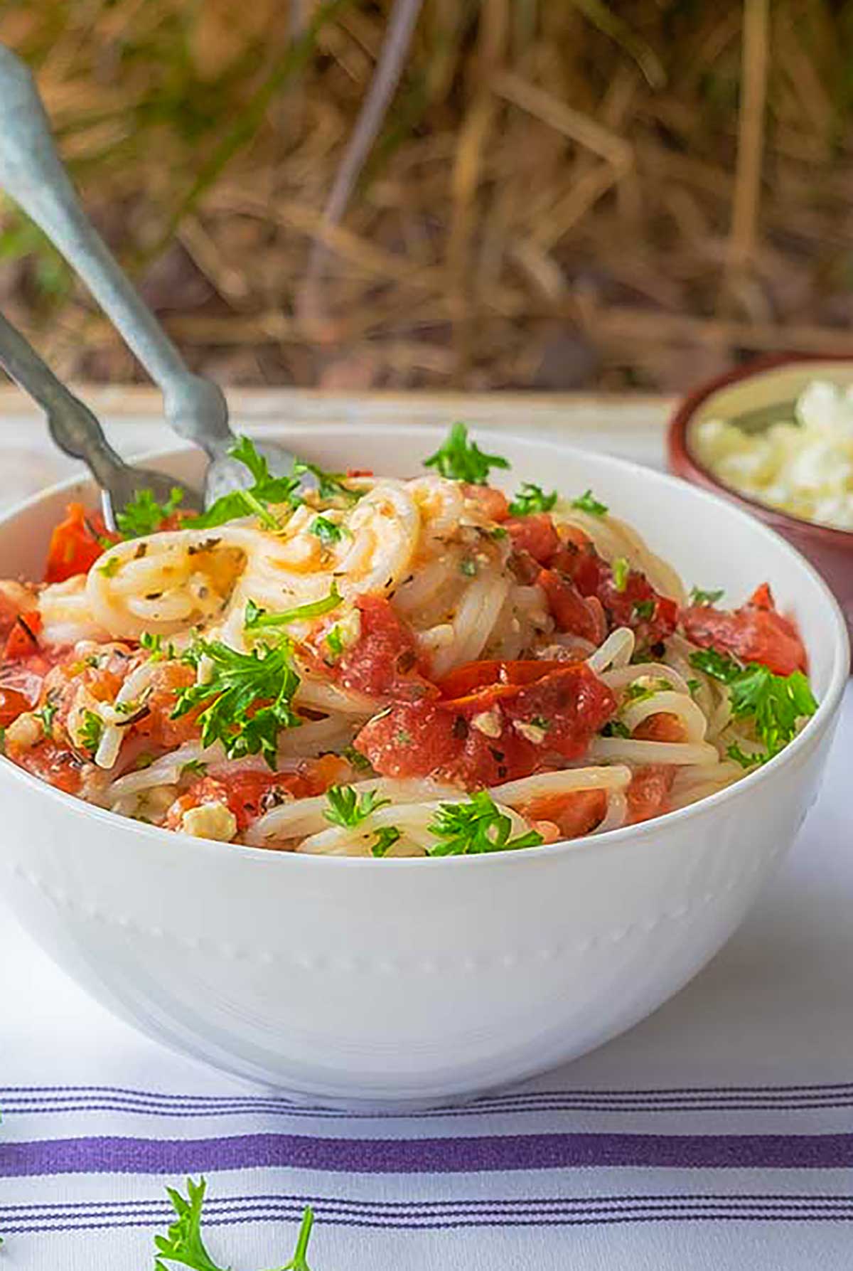 saucy spaghetti with fresh tomatoes and creamy feta with fresh herbs in a bowl