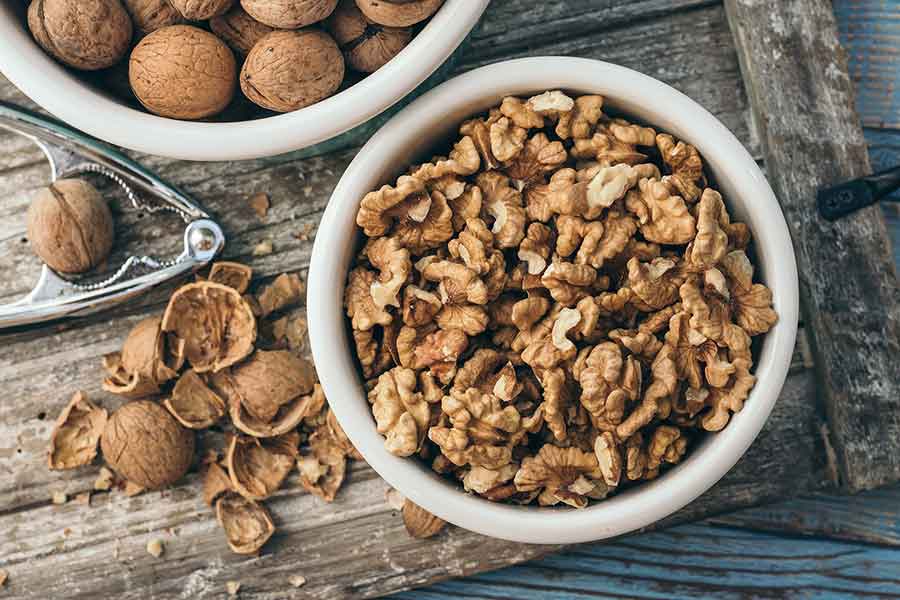 whole and shelled walnuts in. a white bowl