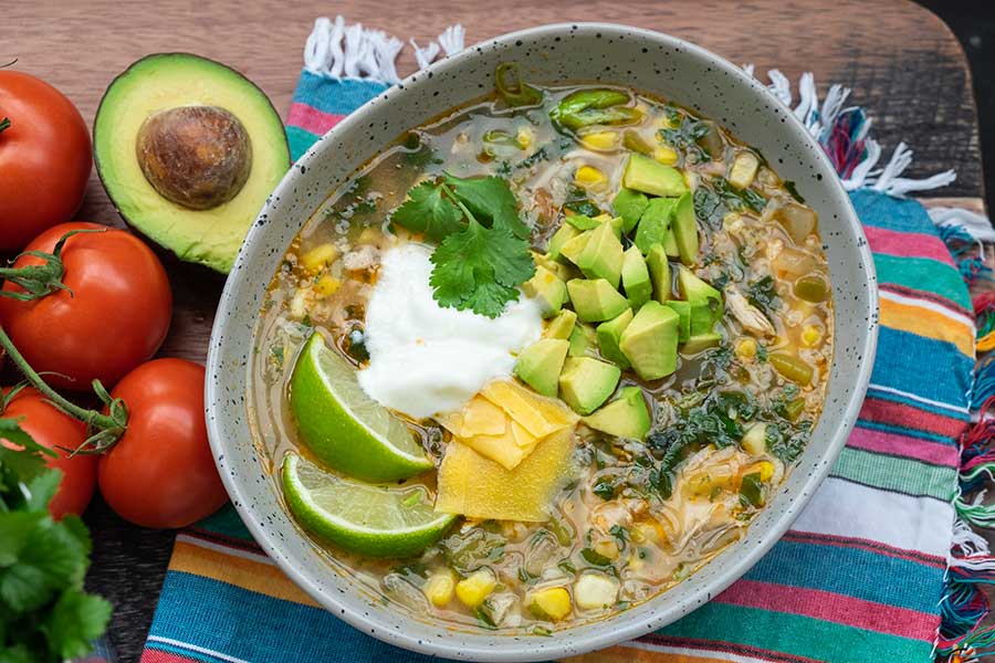 Mexican chicken rice soup in a bowl topped with avocado and lemon slices