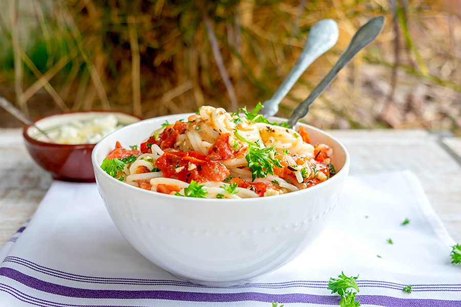 gluten free tomato and feta pasta in a bowl with a fork