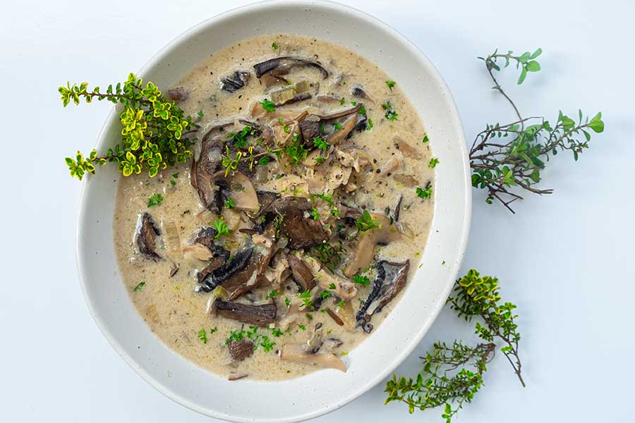 mushroom soup in a bowl topped with fresh thyme