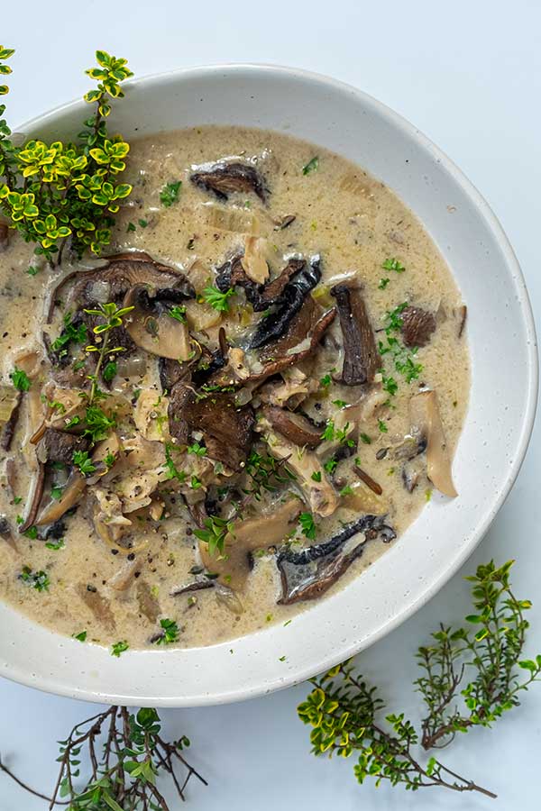 creamy chicken mushroom rice soup in a bowl topped with fresh herbs