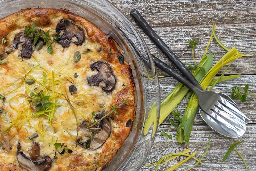 baked crustless quiche with leeks mushrooms and fontina cheese in a pie dish