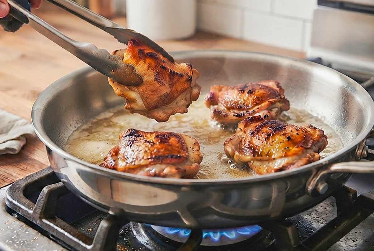 searing chicken thighs with skin on to brown color in a skillet with butter