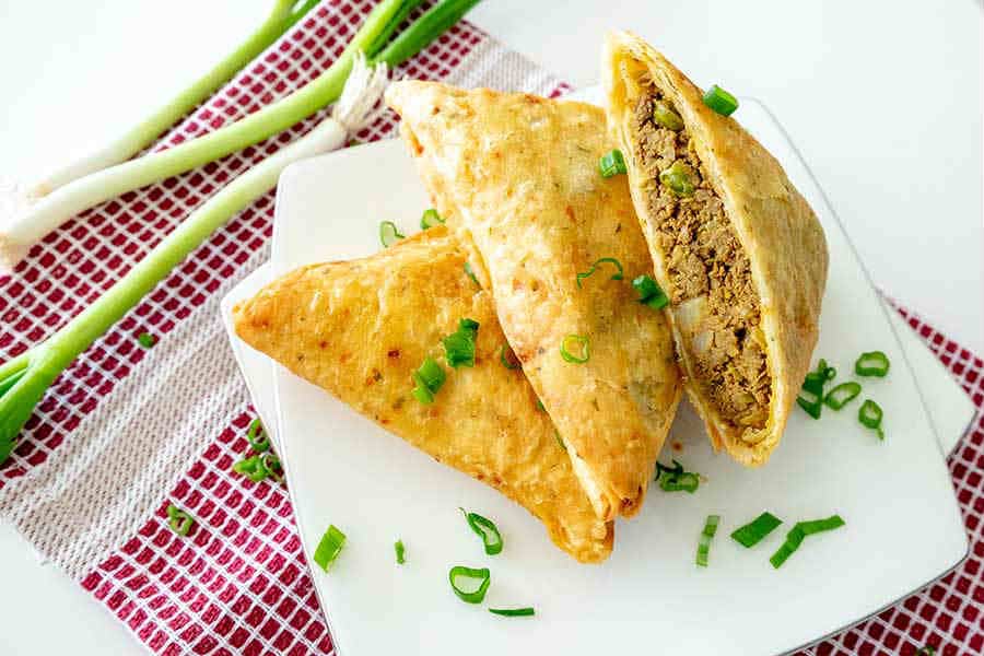 gluten free samosa cut in half on a plate for game day