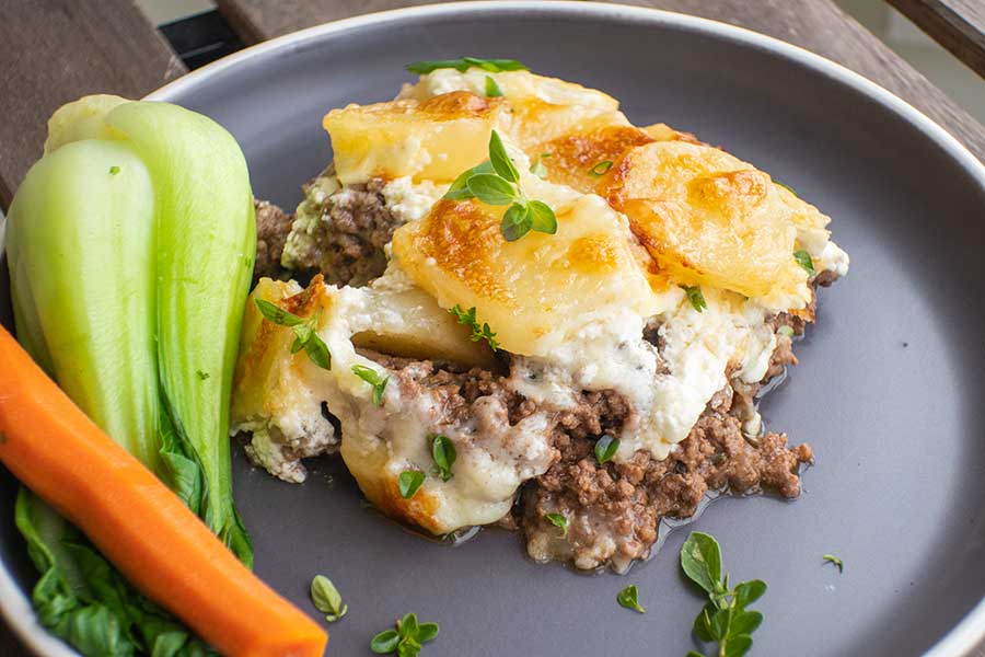 slice of Philly cheesesteak casserole on a plate with veggies