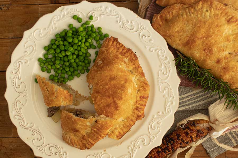 sliced Cornish Pasty on a plate with peas