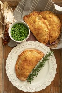 gluten free Cornish Pasty on a plate with a sprig of rosemary
