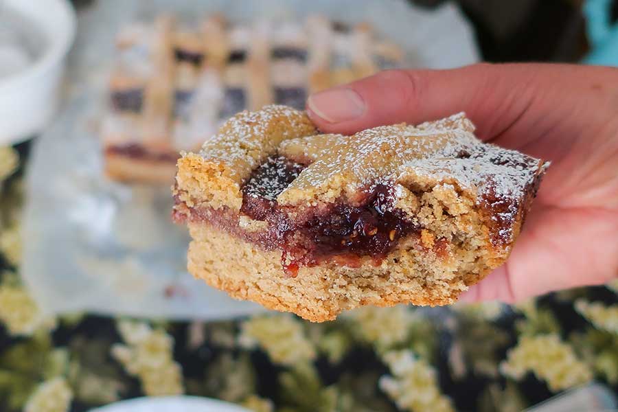 a hand holding a slice of gluten-free linzer cake