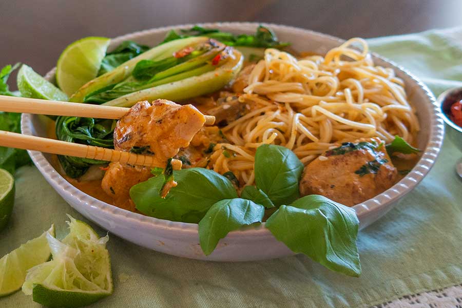 creamy thai chicken noodle dish in a bowl with bok choy