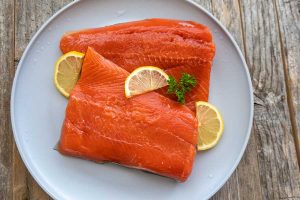 raw salmon fillets on a plate with lemon slices,
