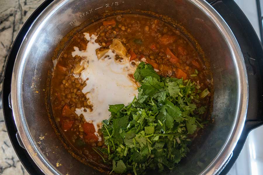 coconut milk and cilantro added to cooked lentil stew into an Instant pot