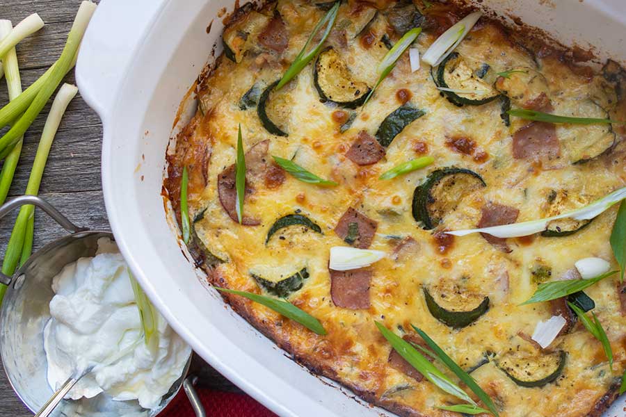 zucchini and ham baked with cheese casserole in a skillet