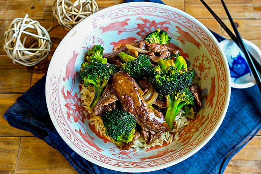 beef and broccoli in a bowl with chopsticks