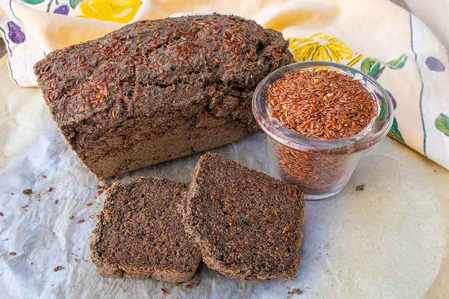 sliced buckwheat flax bread with a bowl of flaxseed