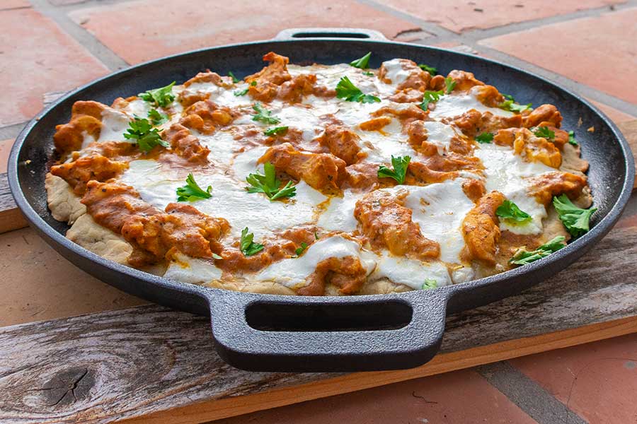 butter chicken pizza on a cast iron skillet