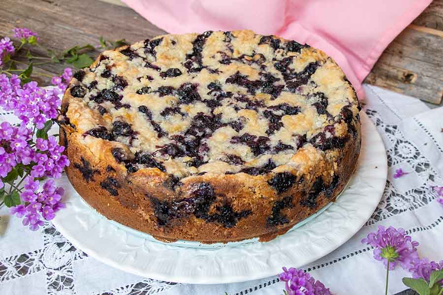 baked round blueberry cream cheese coffee cake on a white plate