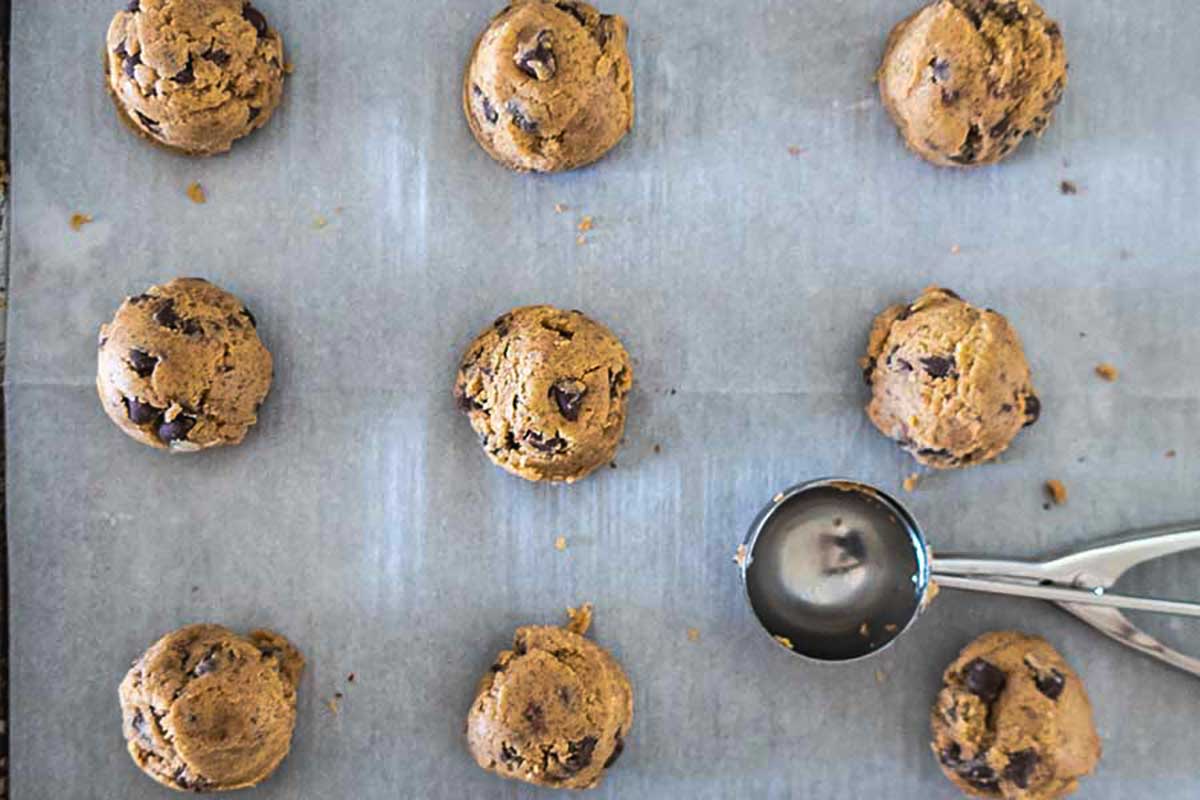 brown butter chocolate chip cookies placed 2" apart on a cookie sheet with cookie scoop before baking
