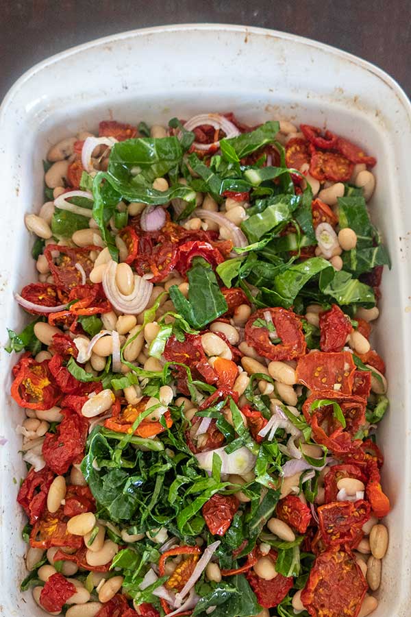 overview of Roast Fish with Cannellini Beans Sundried Tomatoes and Greens in a baking dish before cooking