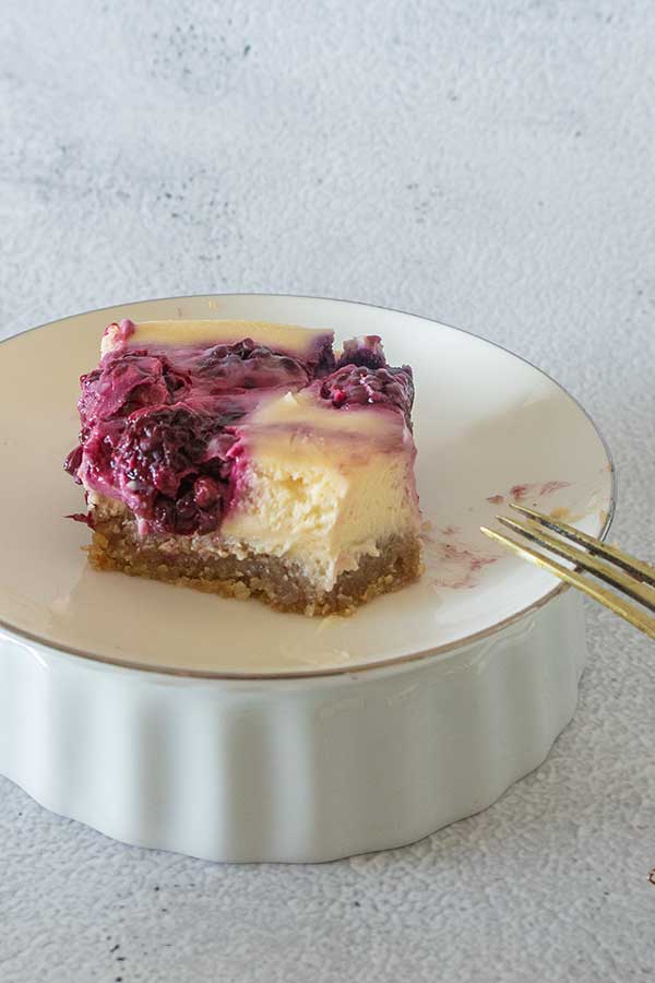 half a slice of grain free berry cheesecake bar on a dessert plate