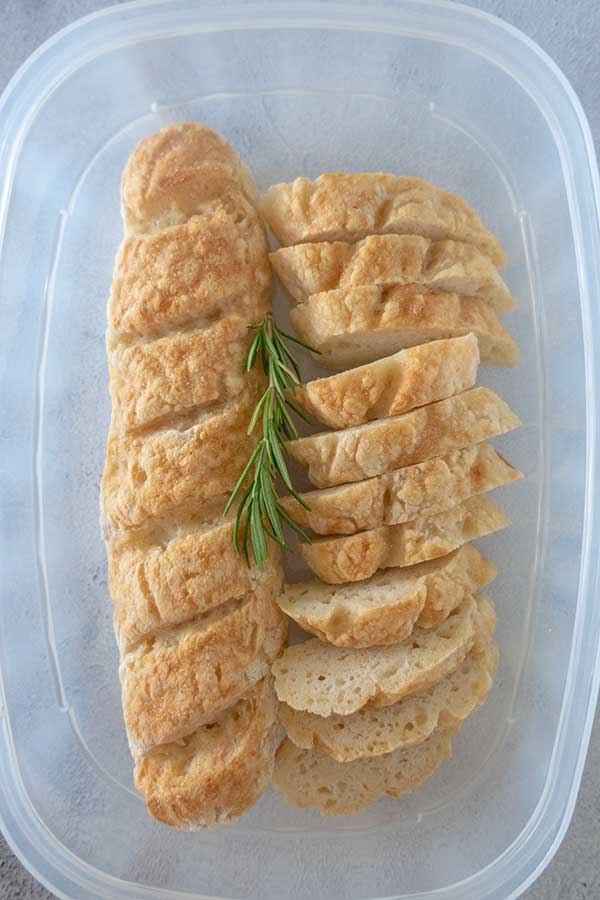 sliced italian bread in a plastic container with rosemary