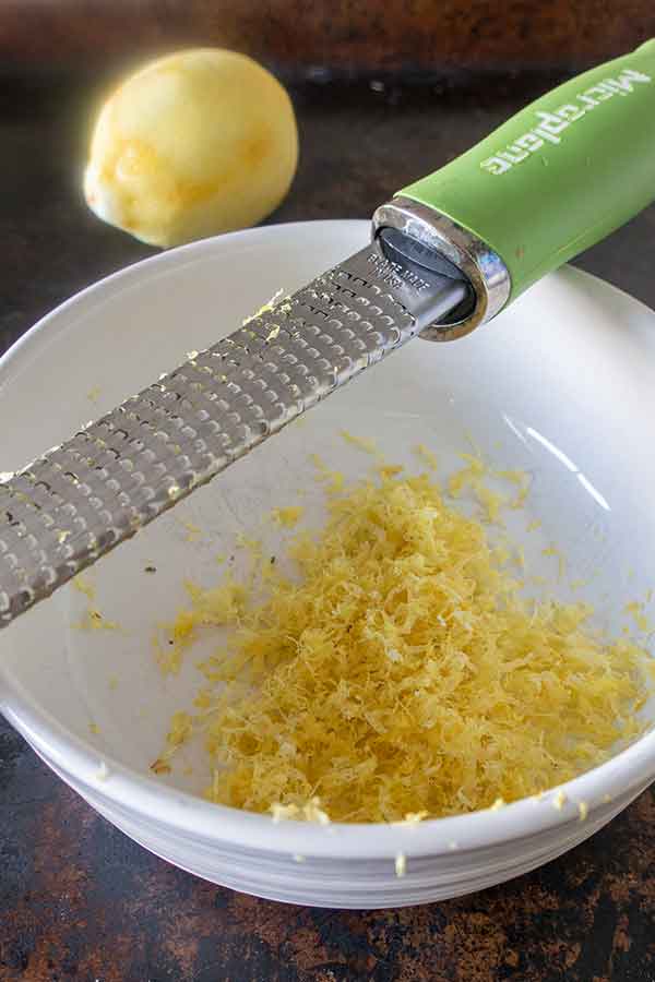 zested lemon in a bowl with microplaner