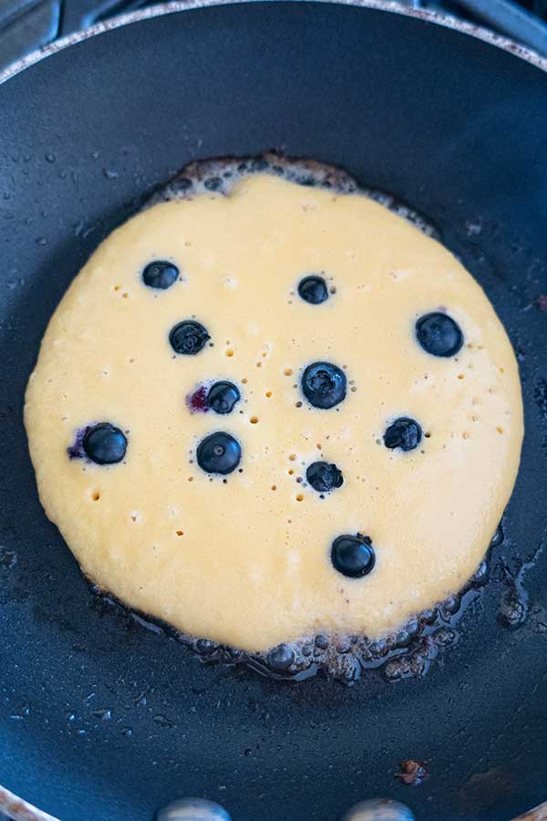cooking pancakes with blueberries in a pan