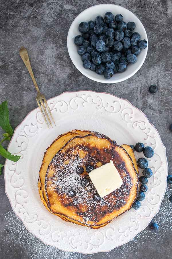 gluten-free blueberry maple pancakes on a plate with butter and fresh blueberries