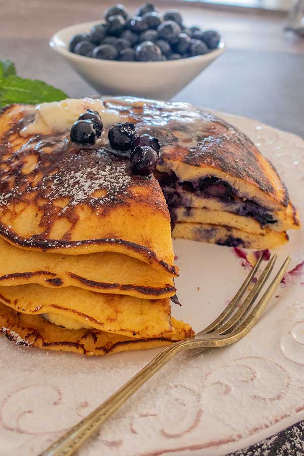 low carb blueberry pancakes stacked on a plate with a fork