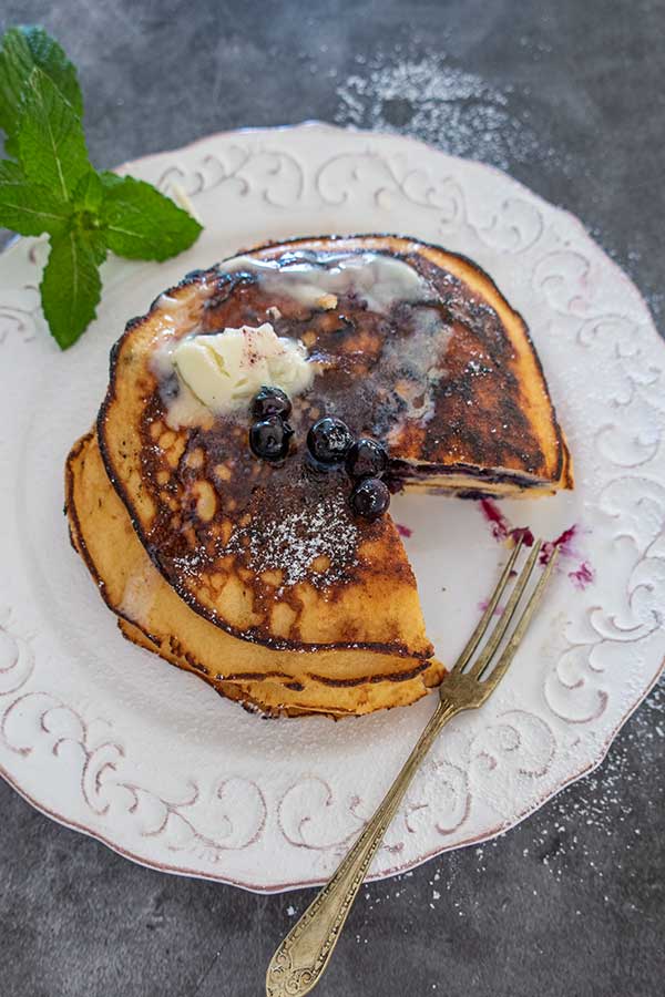 overview of coconut flour pancakes topped with butter on a plate with a fork