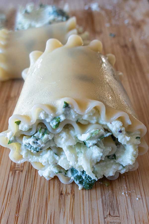 uncooked rolled lasagna noodle with spinach ricotta filling