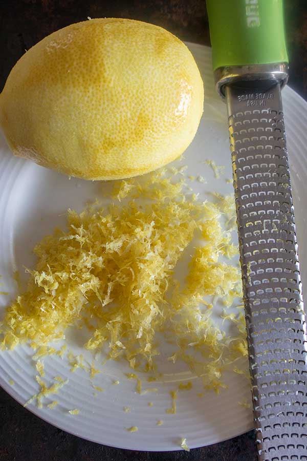 lemon and grated lemon zest on a plate with lemon zester