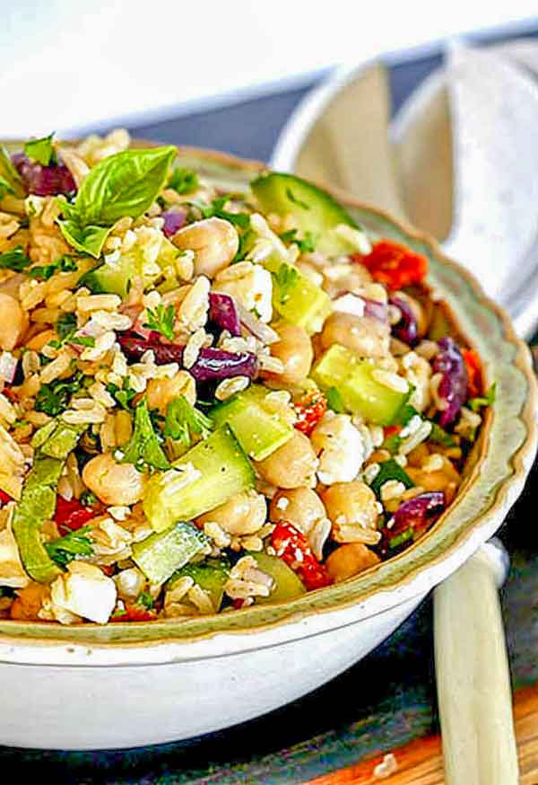 brown rice salad with vegetables and feta in a bowl with gluten-free salad dressing