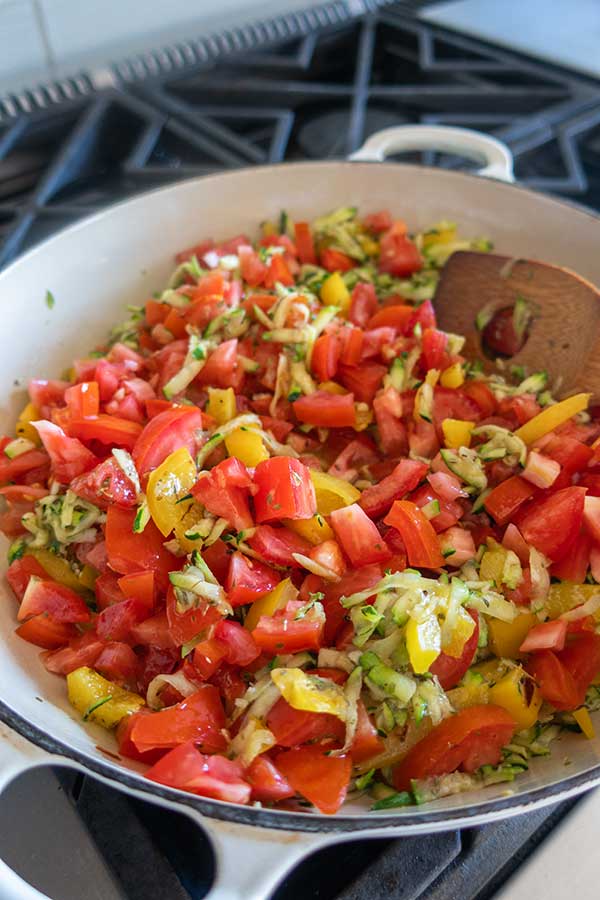 tomatoes zucchini and bell peppers simmering in a skillet