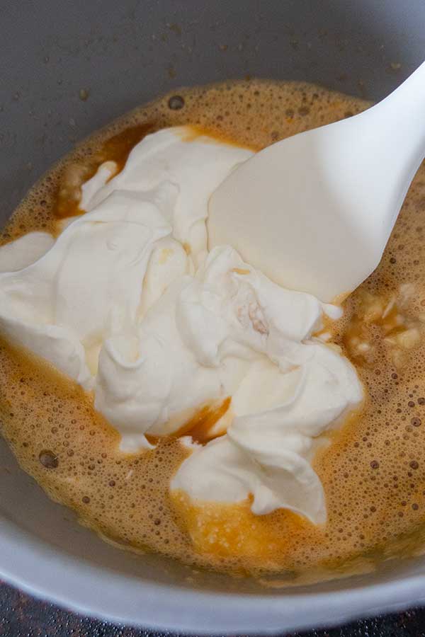 mixing eggs with sour cream in a bowl
