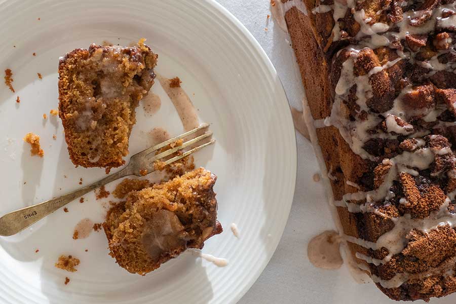 half a slice of an apple fritter bread on a plate with a fork