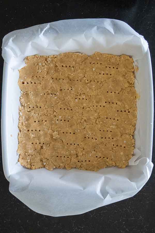 unbaked crust in a square baking pan lined with parchment paper