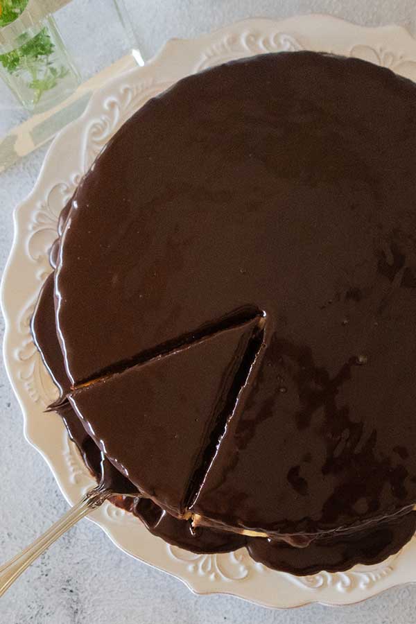 overview of boston cream pie with one slice cut out on a cake platter