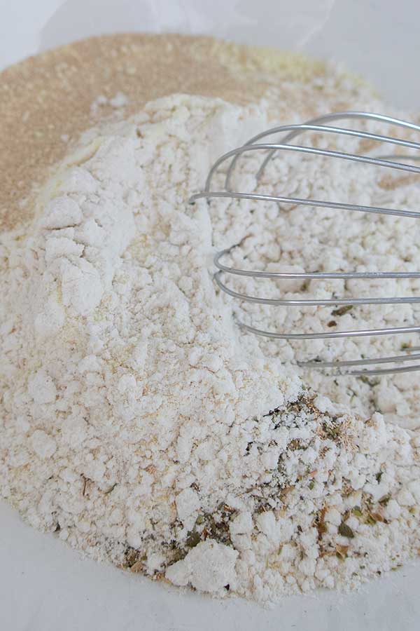 whisking flour yeast and herbs in a bowl