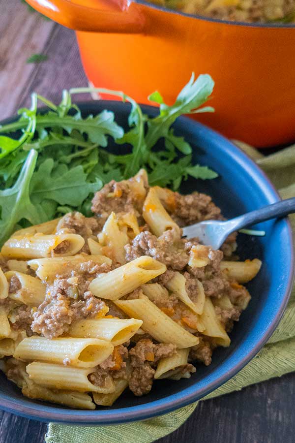 close up of hamburger helper penne in a bowl with a fork